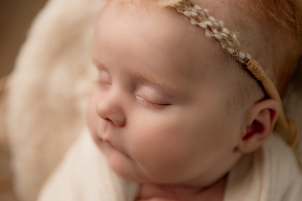 Closeup newborn portrait. Baby eyelashes and facial details are highlighted. 