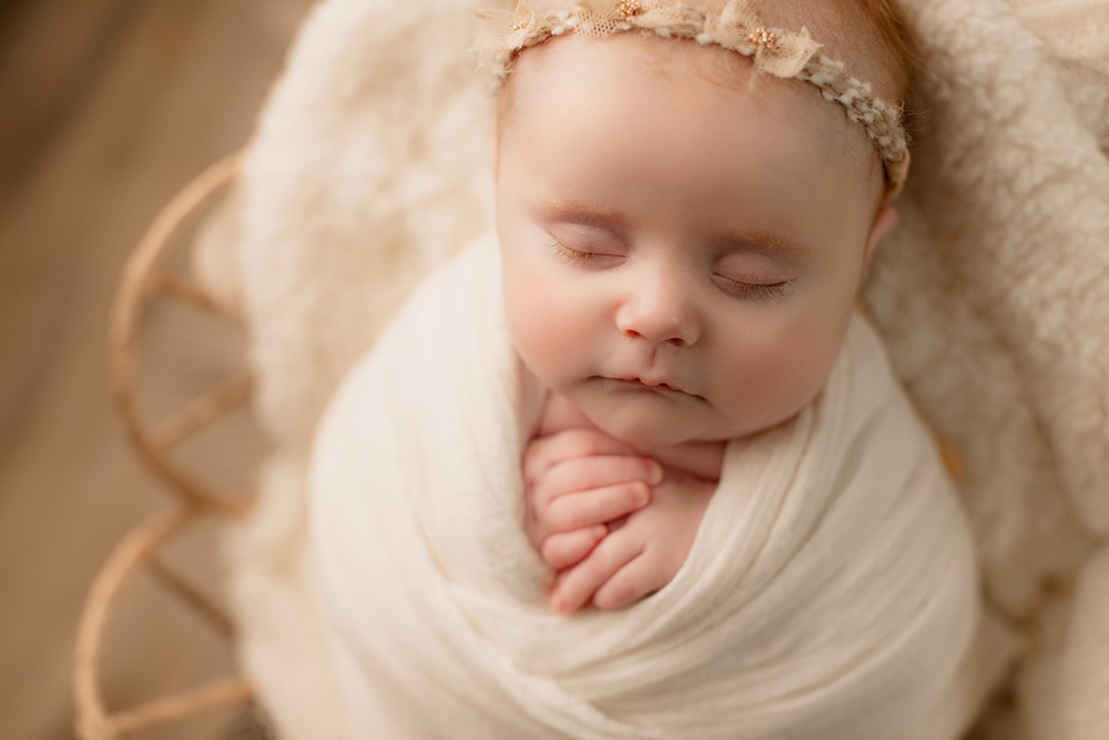 Studio Newborn Portrait Session. Baby wrapped in cream blankets, sleeping peacefully.