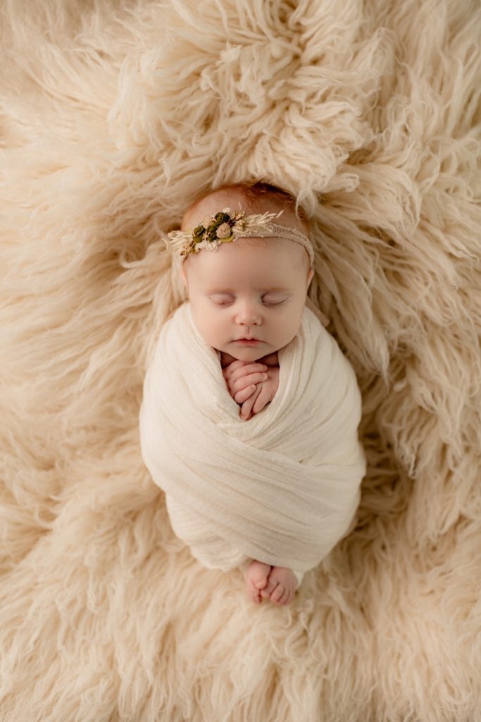 Everly wrapped in a cream blanket on a fuzzy flokati during her newborn portaits. 