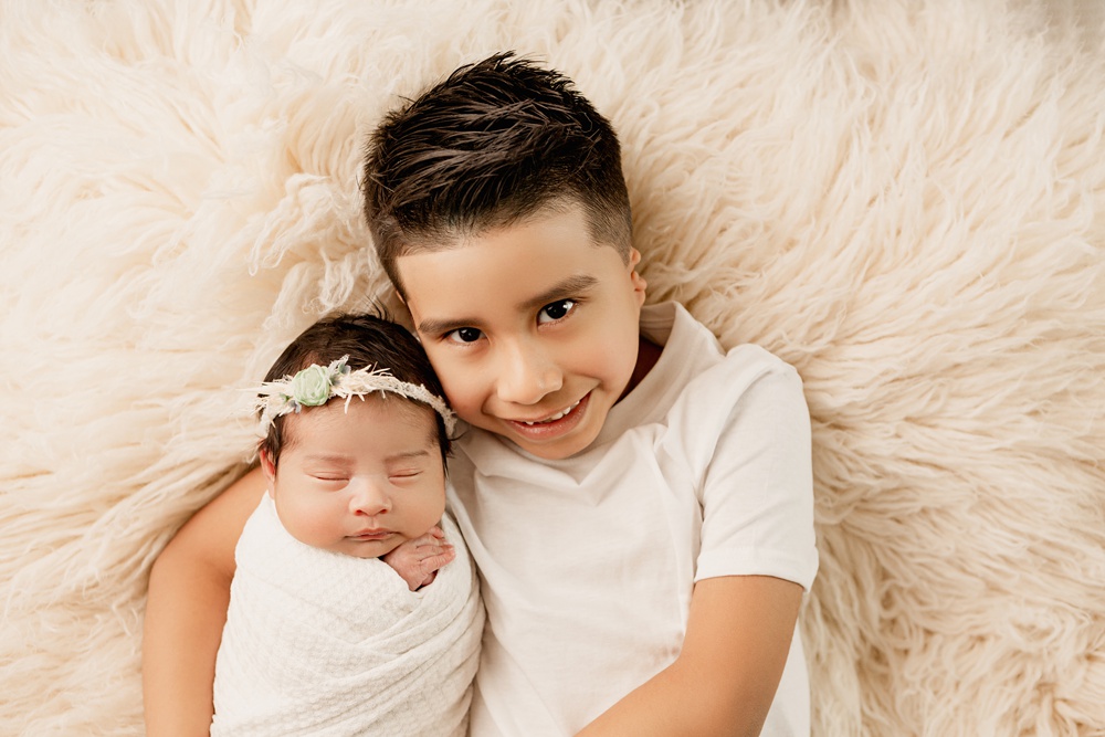 Big brother holds baby sister during their newborn photography session