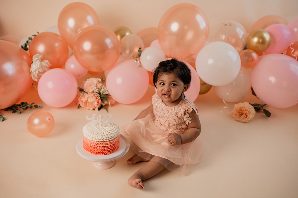 Little girl celebrating her first birthday at a cake smash session